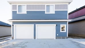A two-story residential building with a garage and a small window on the upper floor.