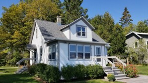 A two-story house with a front porch, a covered staircase, and a well-maintained lawn. -  Clara's Cottage, On Lake Michigan (Oostburg)