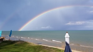 A beach with a rainbow, a white umbrella, and a blue umbrella. -  Clara's Cottage, On Lake Michigan (Oostburg)