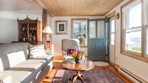 A cozy living room with a sofa, armchair, and a glass coffee table with a vase of flowers. -  Clara's Cottage, On Lake Michigan (Oostburg)