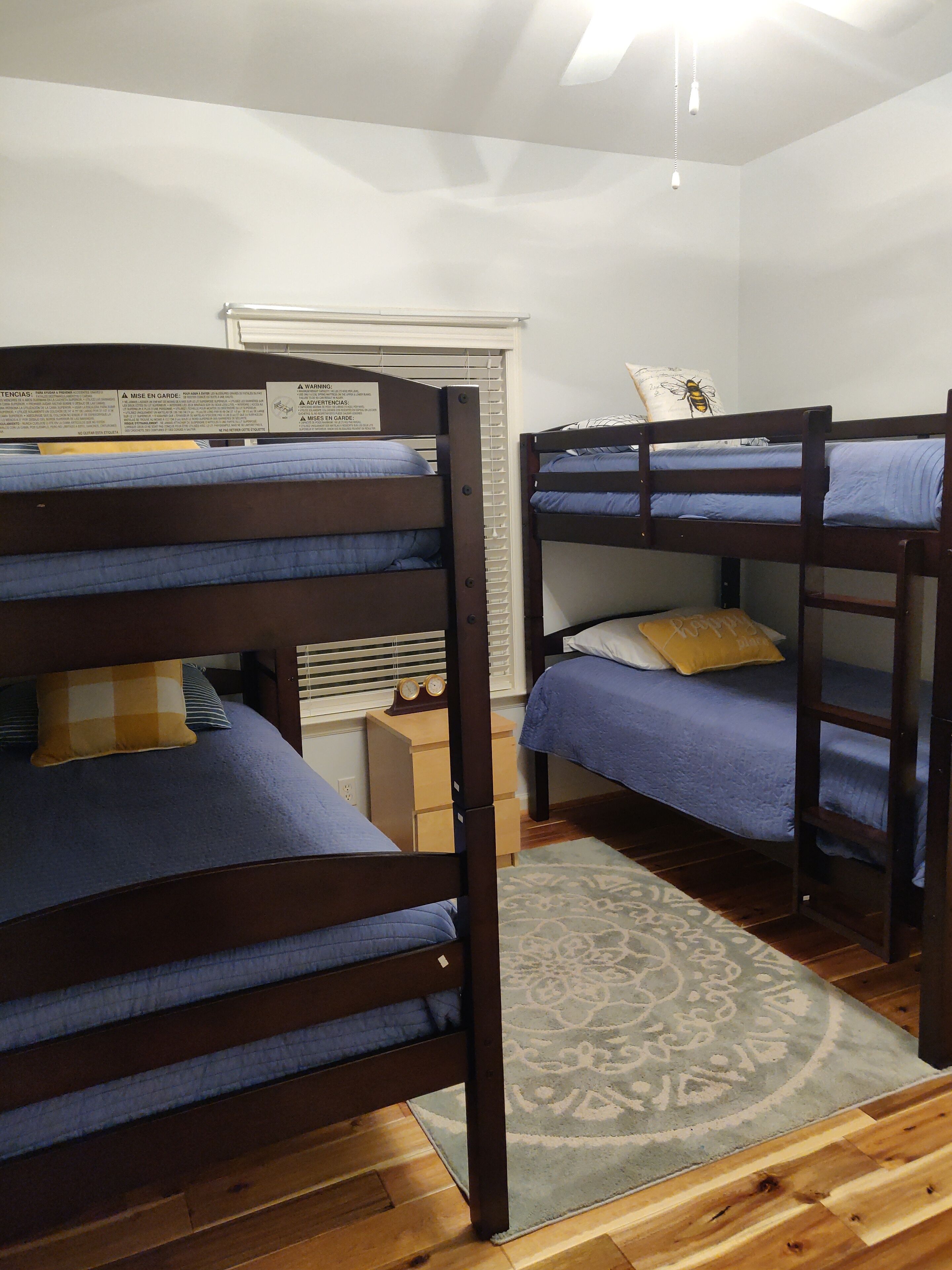 A room with bunk beds, a wooden floor, and a patterned rug.