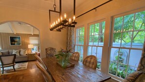 A dining area with a wooden table, chairs, and a hanging light fixture. - Luxury Villa near Siesta - private, heated screened pool (Sarasota)
