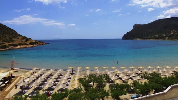 A beach with umbrellas and lounge chairs, a clear sky, and calm sea. - Lemon Tree Suites Near ATH Airport (Markopoulo Mesogaias)