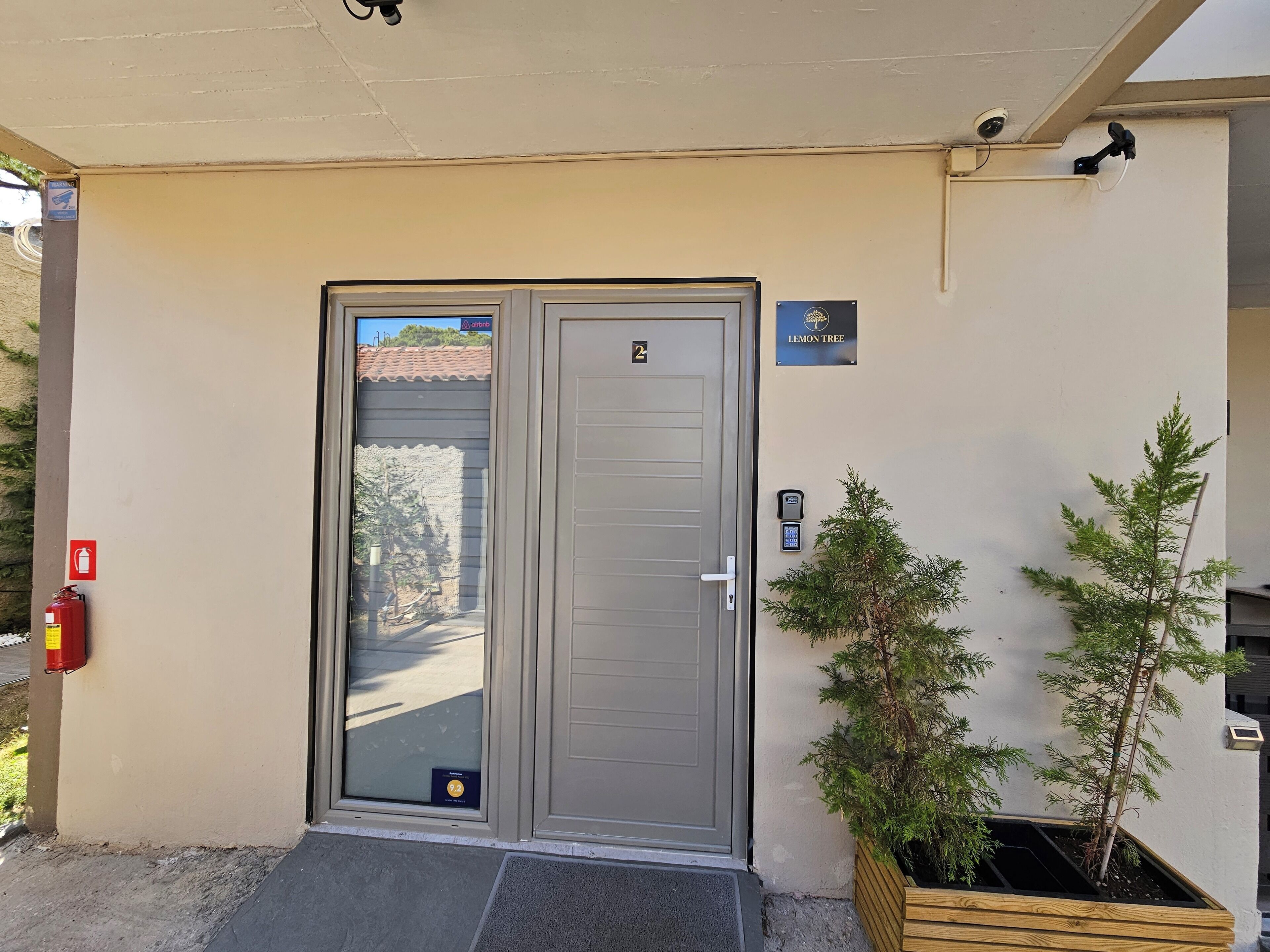 Une entrée à double porte, dotée d’un clavier de sécurité et d’une enseigne indiquant « Lemon Tree ».