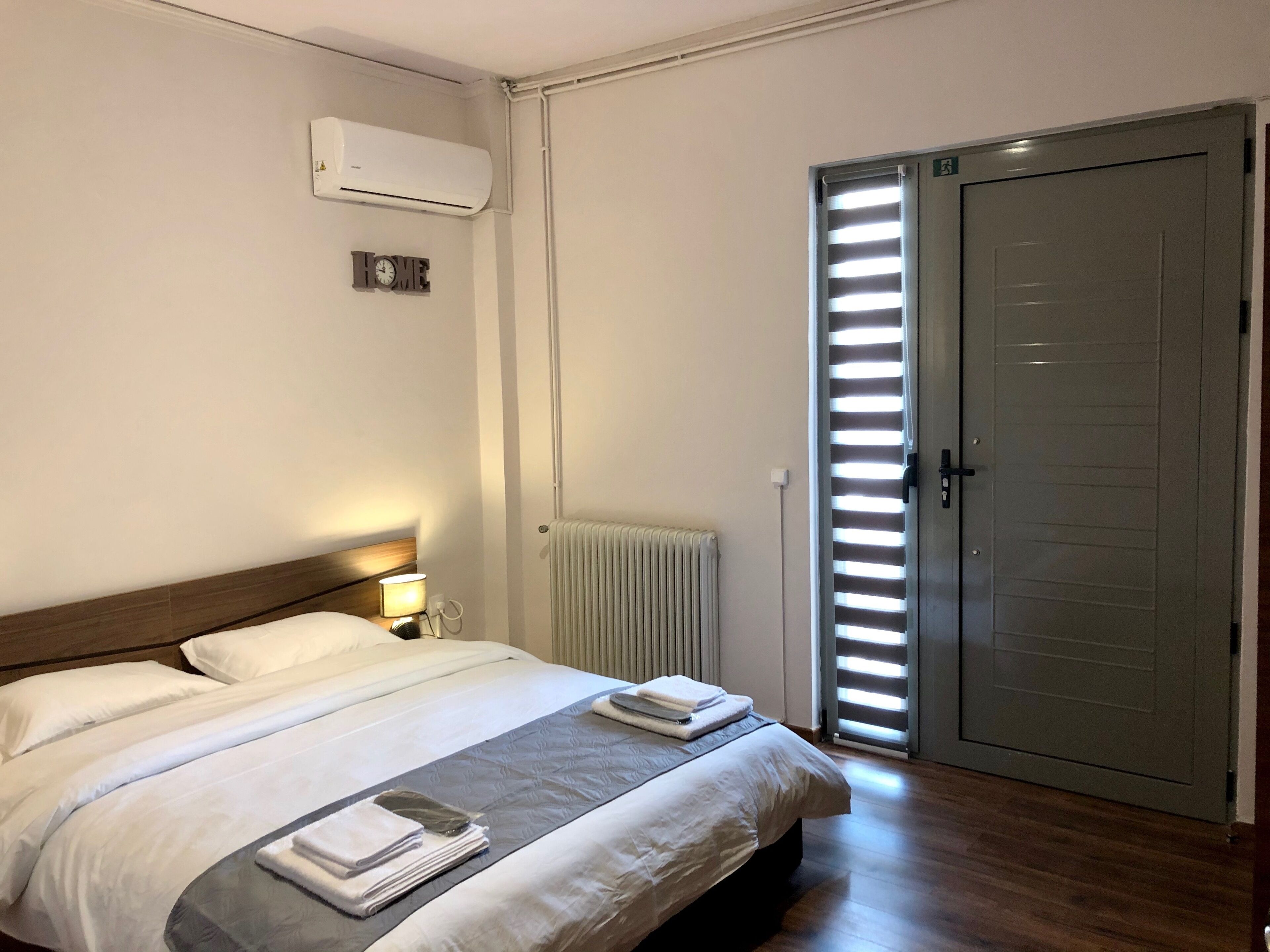 Een hotelkamer met een bed, bedlampje, airconditioning, radiator en een schuifdeur.