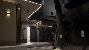 A modern interior with a staircase leading to a door, ambient lighting, and a view of the outdoors. - Lemon Tree Suites Near ATH Airport (Markopoulo Mesogaias)
