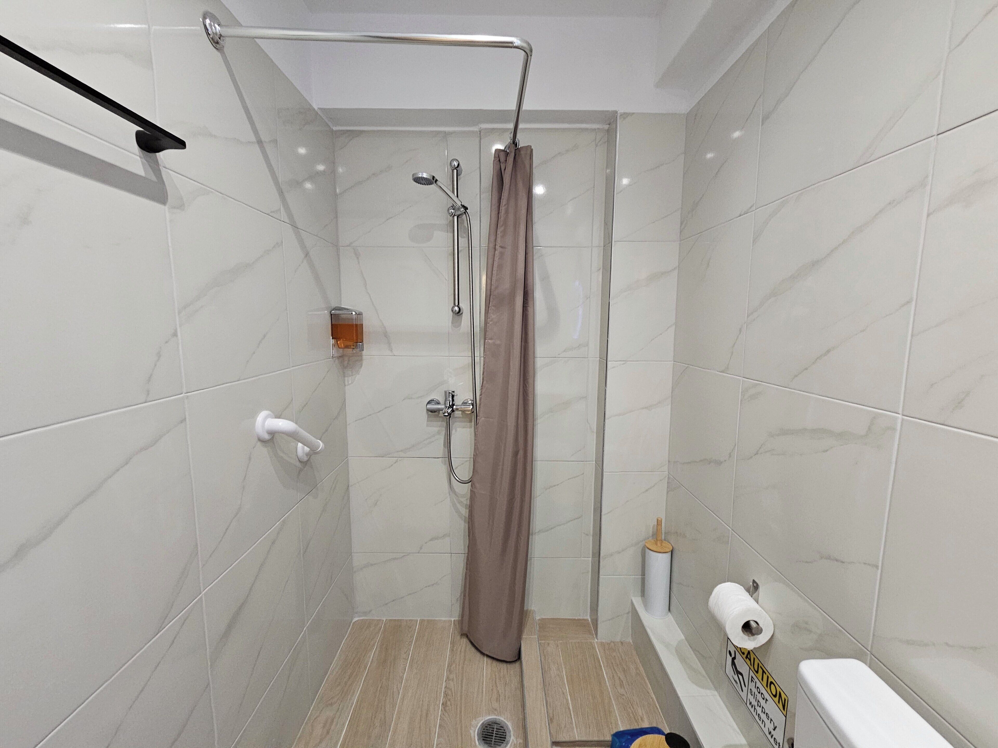 Un baño pequeño y moderno con ducha, inodoro y perchero para toallas.