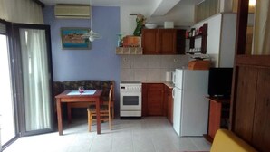 Cocina compacta con comedor, sofá y televisor.
