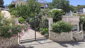 Un área residencial cerrada con muro de piedra, portón metálico y un edificio con balcón.