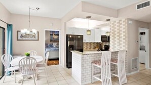 Una cocina moderna con gabinetes blancos, un refrigerador negro y un respingo de azulejos.