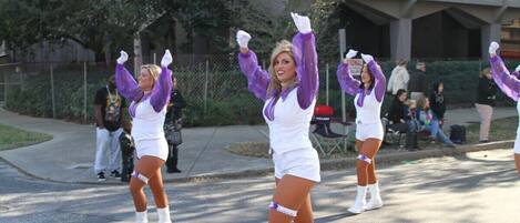 A group of cheerleaders performing in an outdoor setting with a building and spectators in the background.