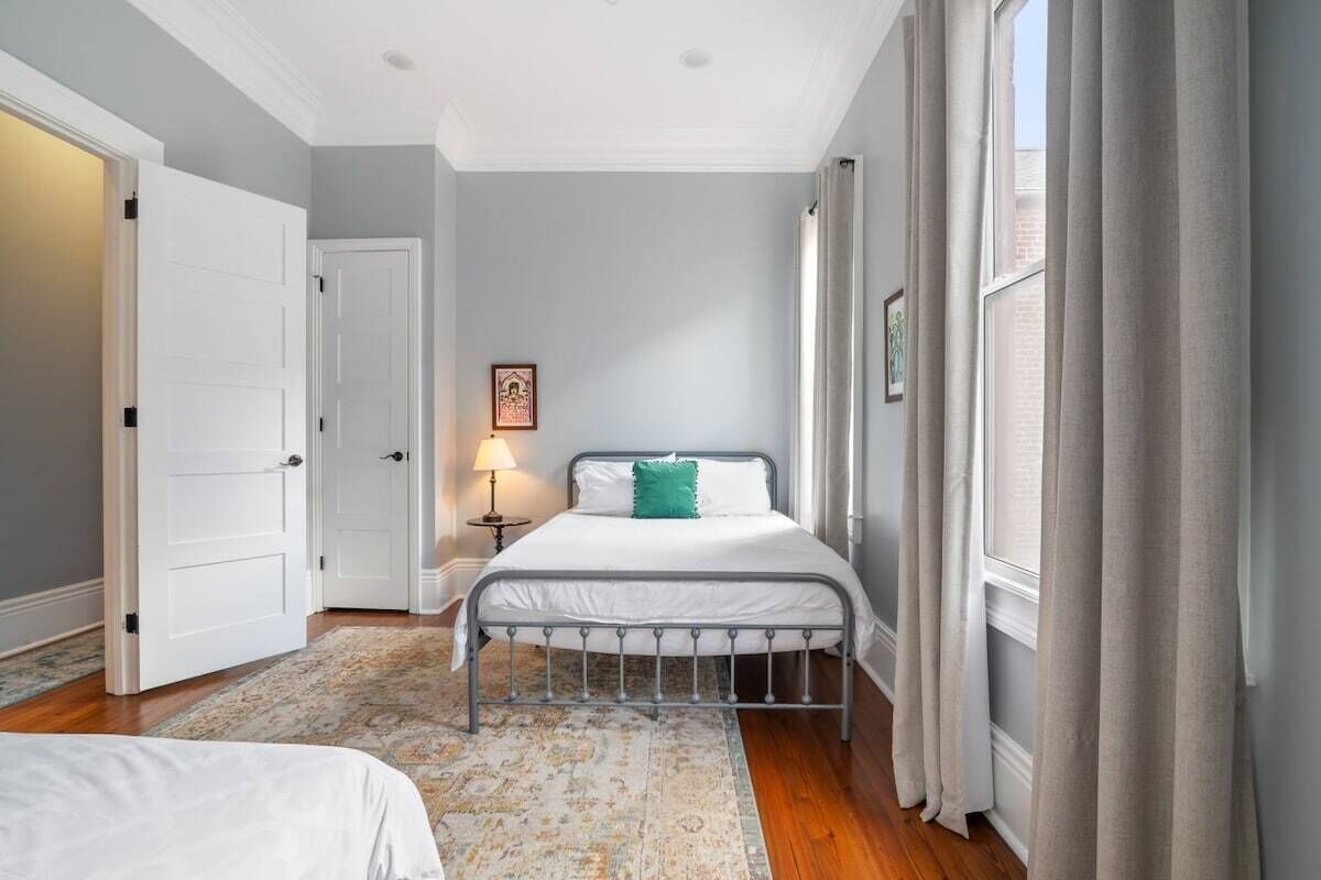 A bedroom with a bed, a nightstand, a lamp, and a window with curtains.