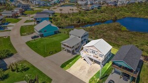 An aerial view of a residential area with houses, a road, and a body of water.