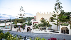 A building with a white facade, arched windows, and a gate. - Inviting Arokaria Apartment in Panormo (Mylopotamos)
