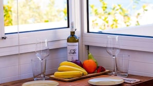 A table with a bottle of wine, two glasses, and a fruit platter. - Inviting Arokaria Apartment in Panormo (Mylopotamos)
