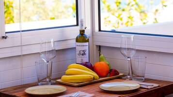 Une table avec une bouteille de vin, deux verres et une assiette de fruits.