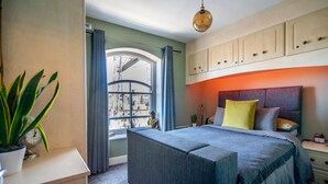 Un dormitorio con una cama, una mesita de noche, cortinas en una ventana y una planta.