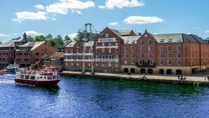 Un edificio histórico de ladrillo rojo con el letrero "Woodmill", ubicación frente al agua y un barco amarrado cerca.