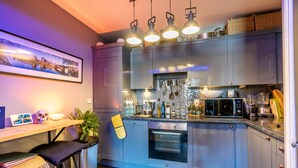 Una cocina moderna con electrodomésticos de acero inoxidable, una barra y un cuadro con una vista urbana enmarcada en la pared.