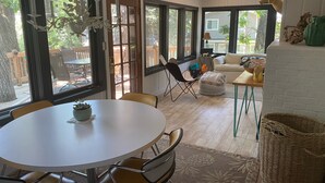 A dining area with a round table and chairs, a sofa, and a wicker basket.