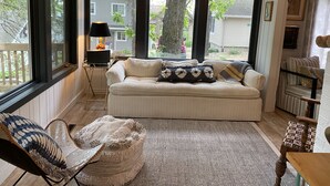 A cozy living room with a sofa, a chair, a lamp, and a view of the outside.