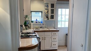 A kitchen with a wooden ceiling, white cabinets, and a window.