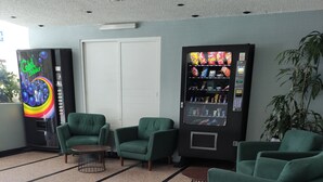 A lobby with green armchairs, a vending machine, and a door. - Hotel Habana (Mexico City)