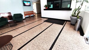 A lobby with a reception desk, seating area, and a television screen. - Hotel Habana (Mexico City)