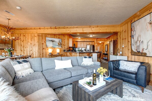 A modern living room with a gray sectional sofa, a black leather armchair, and a wooden coffee table.