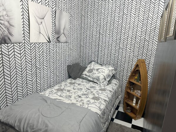 Une chambre à coucher avec un lit, une étagère en bois et un papier peint à motifs.
