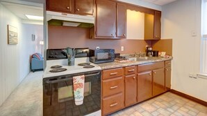 A kitchen with wooden cabinets, a stove, a microwave, and a coffee maker. - Parkview, Apt #5
Parkview Historic Apartment (Hershey)
