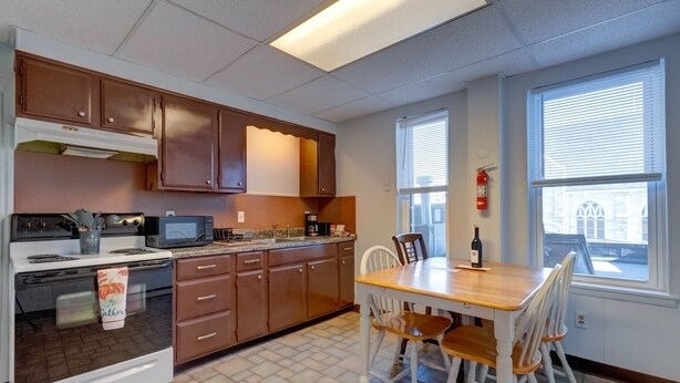 A kitchen with wooden cabinets, a stove, microwave, and a dining table with chairs. - Parkview, Apt #5
Parkview Historic Apartment (Hershey)