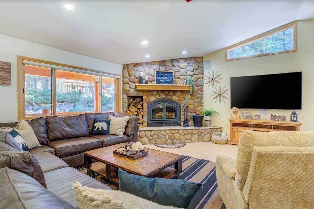 Un salon chaleureux avec une cheminée en pierre, un grand téléviseur à écran plat et un coin salon confortable.