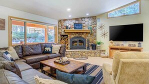 Una sala de estar acogedora con chimenea de piedra, un televisor de pantalla plana grande y un espacio de estar confortable.