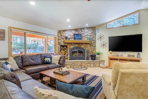 A cozy living room with a stone fireplace, a large flat-screen TV, and a comfortable seating area.