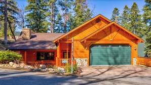 Ein Chalet mit Kamin aus Stein, einer grünen Garagentür und einer Holzfassade.