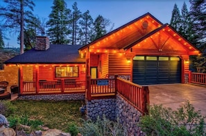 A log cabin with a stone foundation, a covered porch, and a garage.