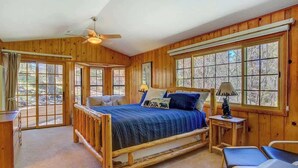 Ein Schlafzimmer einer Holzhütte mit einem Bett, einem Schreibtisch und einem Stuhl.