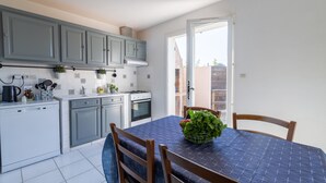A compact kitchen with grey cabinets, a white countertop, and a dining table with a blue tablecloth.