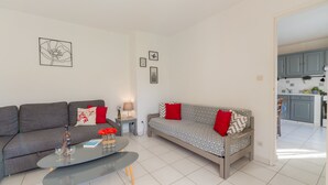 A modern living room with a grey sofa, a patterned sofa, a coffee table, and a small side table with a lamp.