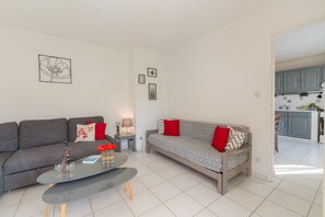 A modern living room with a grey sofa, a patterned sofa, a coffee table, and a small side table with a lamp.