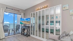 A room with a TV, a desk, a sofa, a balcony with chairs, and a mirrored wardrobe. - Palace 2101 (Myrtle Beach)