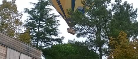 Un globo aerostático con la inscripción "EN PROVENCE" sobrevolando un edificio con porche y terraza.
