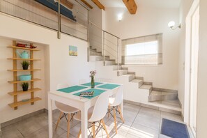 A modern interior with a dining area, staircase, and a view of the outside.