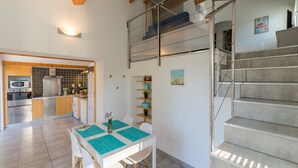 Eine moderne Küche mit Essbereich, einer Treppe und Blick zum Wohnzimmer.
