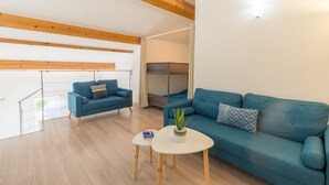 Ein modernes Wohnzimmer mit einem blauen Sofa, einem kleinen weißen Tisch und einem Blumentopf.