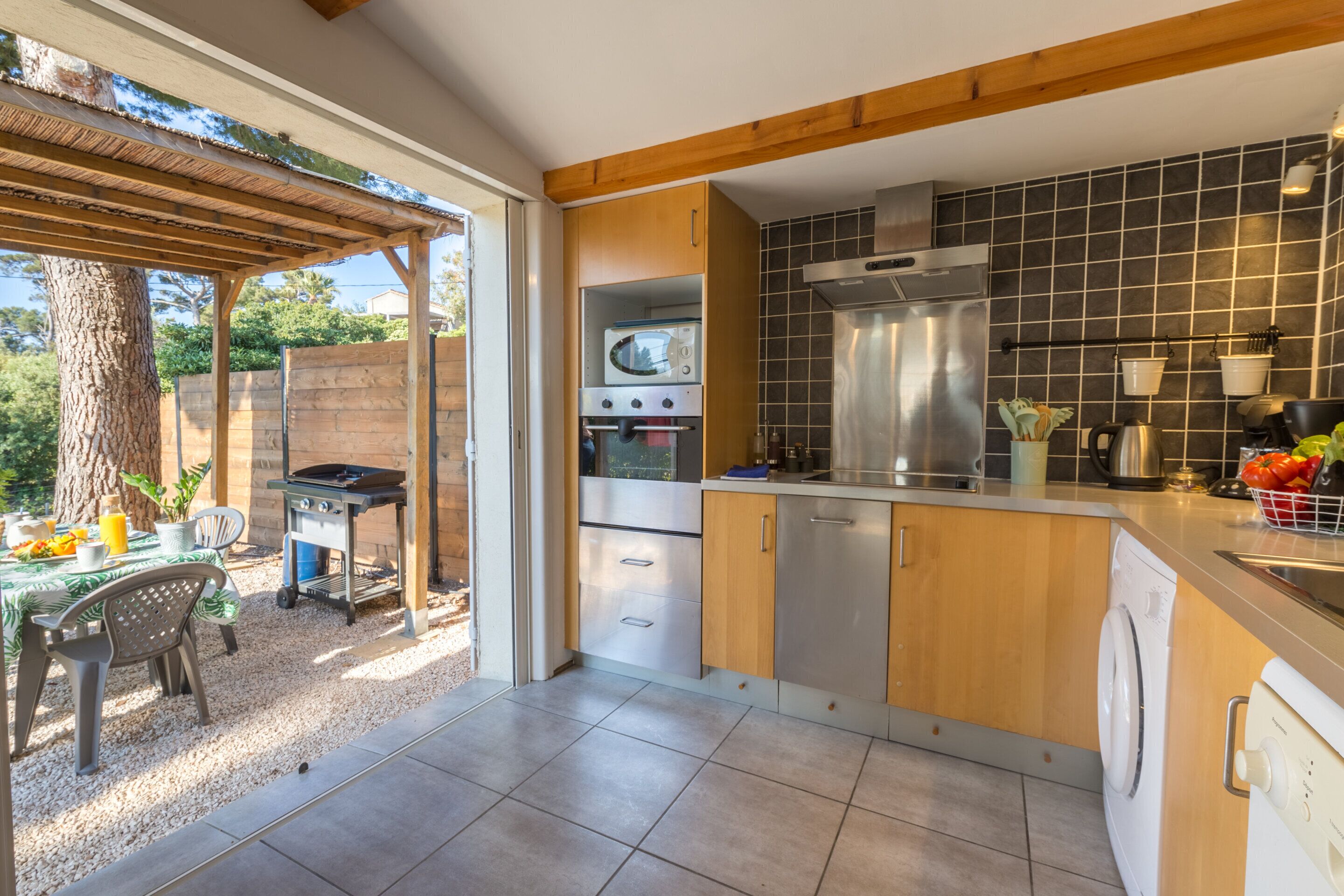 Eine moderne Küche mit Holzschränken, einem eingebauten Backofen und einem großen Fenster.