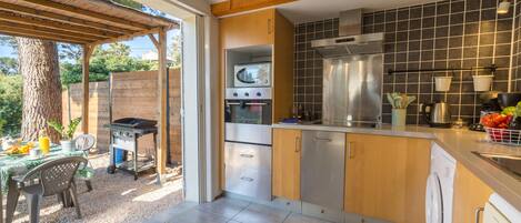 Eine moderne Küche mit Holzschränken, einem eingebauten Backofen und einem großen Fenster.