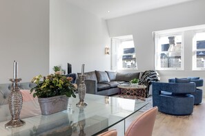 A modern living room with a glass coffee table, grey sofas, and a blue armchair. - Stunningly Decorated 3BD Flat in Fulham (London)