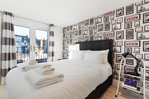 Une chambre d’hôtel avec un grand lit, une table de chevet avec une lampe et un mur décoré de tableaux encadrés.